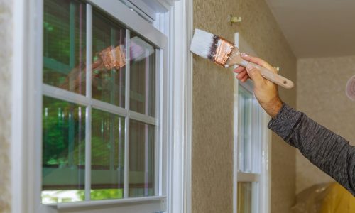Painter painting a window trim or molding of a house